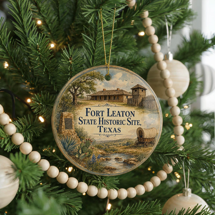 A round ornament hanging on a Christmas tree, featuring an illustration of Fort Leaton, the historic site in Texas.