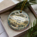 A decorative ornament with a picture of Fort McKayett State Historic Site in Texas, featuring a desert landscape with a cactus and a building.