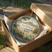 A circular ornament in a wooden box, featuring an illustration of Fort McKeitt, the historic site in Texas.
