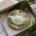 A decorative ornament in a box, featuring a scenic landscape with a house and trees, with the text "Fort Parker State Park, Texas" prominently displayed.