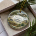 A decorative ornament with a picture of Fort Pillow State Historic Park in Tennessee, featuring a wooden cabin and a mountain landscape.