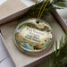 A decorative ornament in a box, featuring an illustration of Fort Sisset Historic State Park, South Dakota, with a buffalo in the foreground.