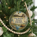A round ornament hanging on a Christmas tree, featuring illustrations of Fort Sisset Historic State Park, South Dakota, with a buffalo in the foreground.