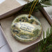 A decorative ornament in a box, featuring a scenic image of Fort Washington State Park, Pennsylvania.