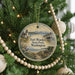 A round ornament hanging on a Christmas tree, featuring a scenic image of Fort WORDEN State Park in Washington.