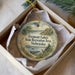 A decorative ornament in a box, featuring a scenic landscape with a lake, mountains, and a deer.