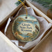 A decorative ornament in a box, featuring an illustration of Glendo State Park in Wyoming with a bird perched on a rock.