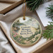 A decorative ornament with a bird perched on a tree branch, surrounded by flowers and greenery, placed inside a box.