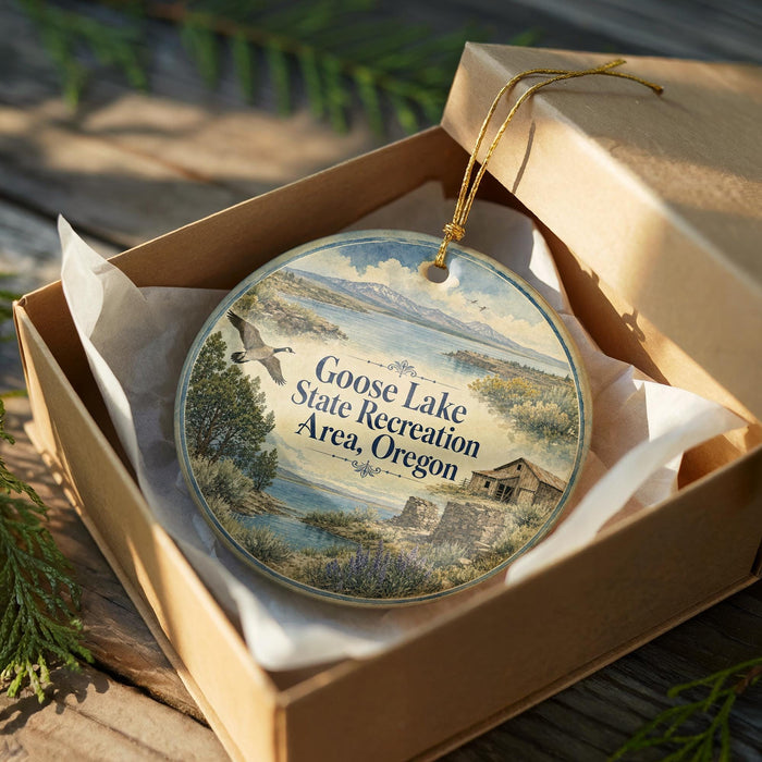 A decorative ornament in a wooden box, featuring a scenic landscape with a lake, mountains, and a bird in flight.