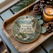 A decorative ornament featuring a scenic landscape of Gorges State Park in North Carolina, with pine cones and a lit candle on a wooden tray.