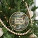 A round ornament hanging on a Christmas tree, featuring a scenic landscape with a waterfall and mountains.