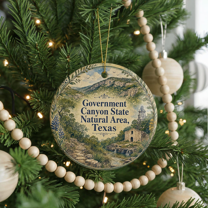 A round ornament hanging on a Christmas tree, featuring a scenic landscape of the Government Canyon State Natural Area in Texas.
