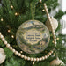 A round ornament hanging on a Christmas tree, featuring a scenic landscape of the Government Canyon State Natural Area in Texas.