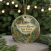 A round ornament with a scenic forest landscape and a deer, hanging on a string.