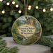 A circular ornament with a scenic landscape of Governor Nelson State Park, Wisconsin, featuring a waterfall, pine trees, and a cabin.
