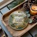 A decorative ornament featuring a scenic image of Grahams Island State Park, North Dakota, with a bench and pine cones on a wooden tray.