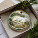 A decorative ornament featuring a scenic landscape of Grahams Island State Park in North Dakota, with a bench and a deer in the foreground.