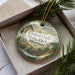 A decorative ornament in a box, featuring a scenic landscape with a bridge and greenery, with the text "Grand Gulf State Park, Missouri" prominently displayed.