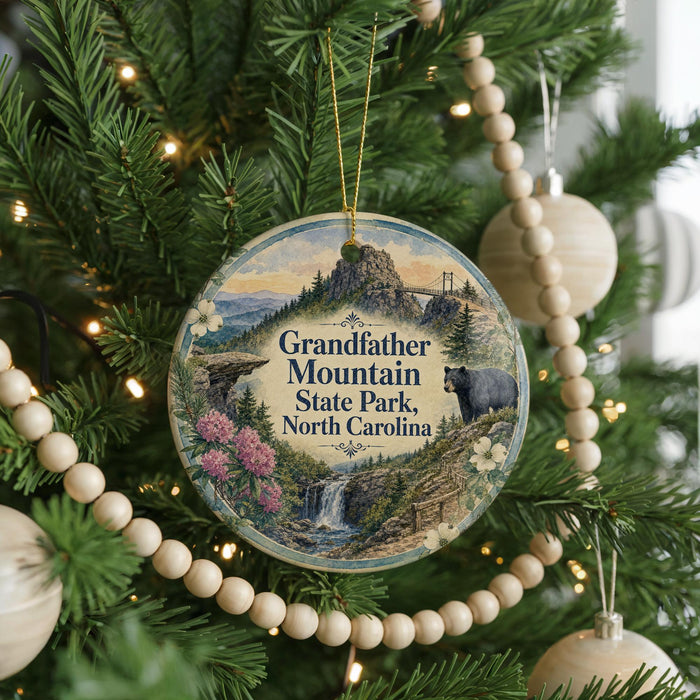 A round ornament hanging on a Christmas tree, featuring a scenic image of Grandfather Mountain State Park in North Carolina.