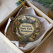 A decorative ornament in a box, featuring a scenic landscape with a waterfall and mountains, along with the text "Granite State Park, Montana".