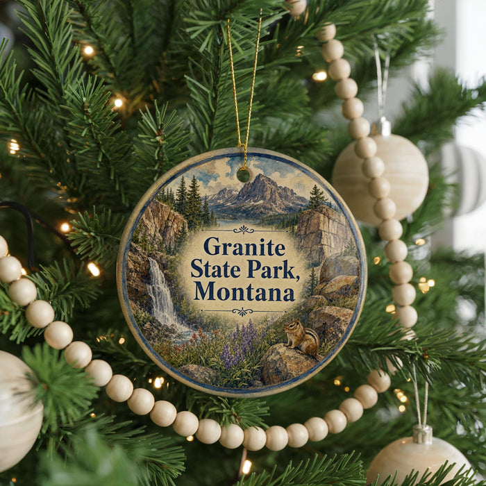 A round ornament hanging on a Christmas tree, featuring a scenic image of Granite State Park, Montana.