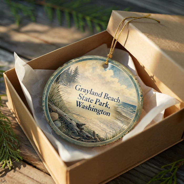 A circular ornament in a wooden box, featuring a scenic beach landscape with pine trees and a body of water.