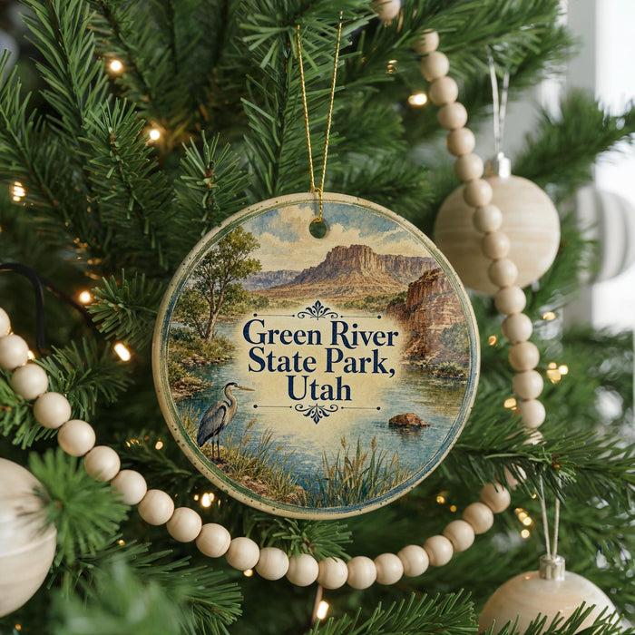 A round ornament hanging on a Christmas tree, featuring a scenic image of the Green River State Park in Utah.