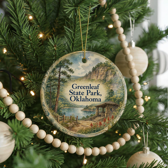 A Christmas tree decorated with ornaments, including a circular ornament with a scenic landscape of Greenleaf State Park, Oklahoma.