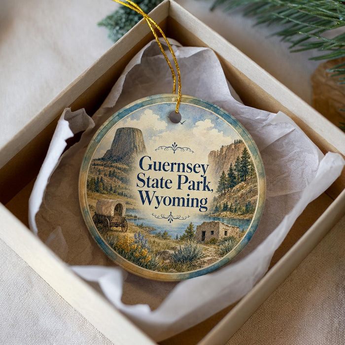 A decorative ornament in a box, featuring a scenic image of Guernsey State Park, Wyoming.