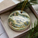 A decorative ornament in a box, featuring a scenic landscape with a lake, trees, and a bird, along with the text "Guilford Lake State Park, Ohio".