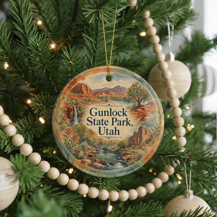 A round ornament hanging on a Christmas tree, featuring a scenic landscape with mountains, waterfalls, and greenery.