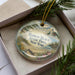 A decorative ornament in a box, featuring a scenic landscape with a lighthouse and beach, along with the text "HAMLIN BEACH STATE PARK, NEW YORK".