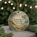 A round ornament with a lighthouse and beach scene, surrounded by greenery and a string of lights.