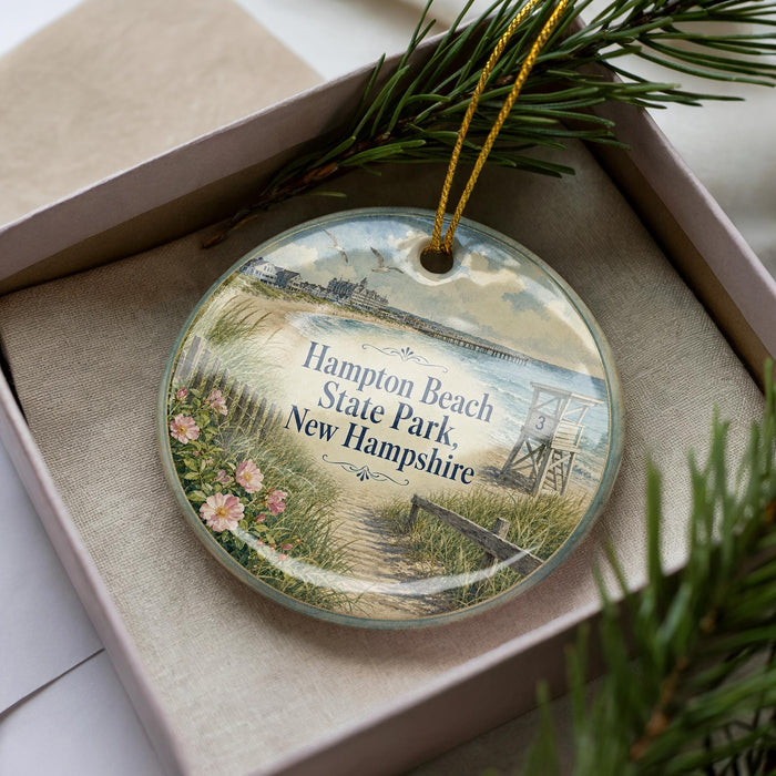 A decorative ornament in a box, featuring a beach scene with a lifeguard tower and a path leading to the beach.