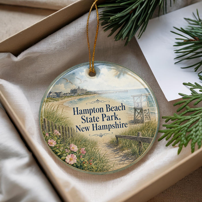 A decorative ornament with a beach scene and a lifeguard tower, placed in a box with pine branches.