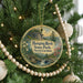 A round ornament hanging on a Christmas tree, featuring a scenic landscape with a waterfall and a bridge.