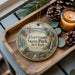 A wooden tray with a decorative ornament featuring a scenic landscape of Harriman State Park, New York, and pine cones.