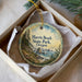 A round ornament with a scenic landscape of Harris Beach State Park, Oregon, displayed in a box with a white tissue paper lining.