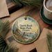 A decorative ornament with a scenic landscape of Harris Beach State Park, Oregon, featuring a winding path, rocky cliffs, and a body of water.