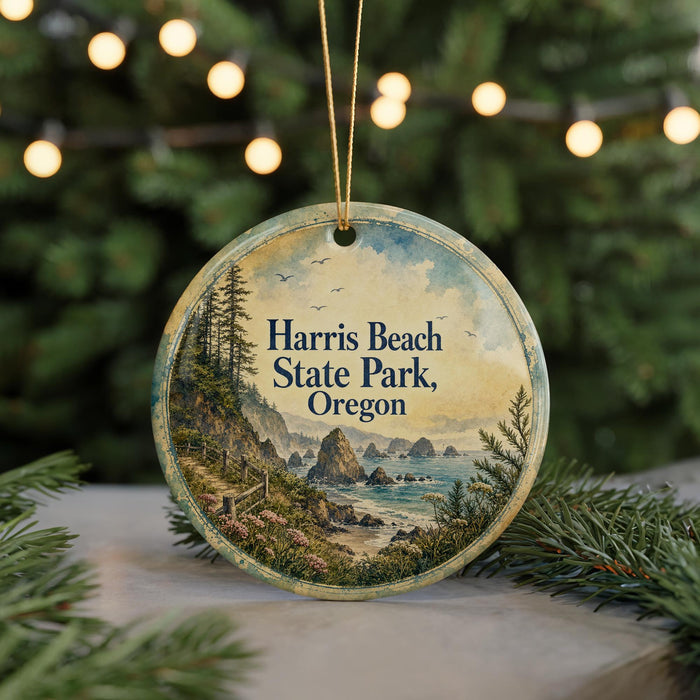 A round ornament with a painting of a coastal landscape, featuring a beach, mountains, and a body of water, hanging from a string.