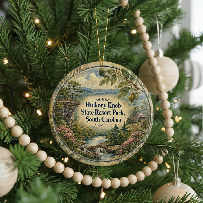 A round ornament hanging on a Christmas tree, featuring a scenic landscape with a river, mountains, and trees.