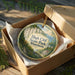 A decorative ornament in a wooden box, featuring a scenic landscape with a cliff and a lake, with the text "High Cliff State Park, Wisconsin" printed on it.