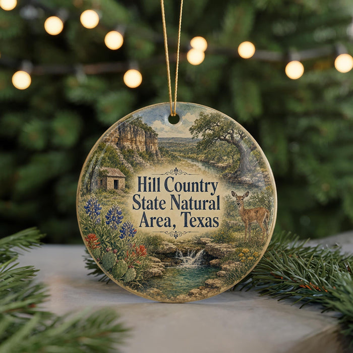 A round ornament with a painting of a natural landscape, featuring a deer, a stream, and a house, hanging from a string.