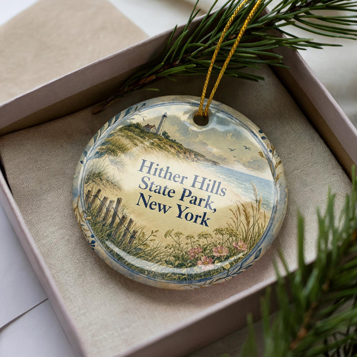 A decorative ornament in a box, featuring a scenic landscape with a lighthouse and a beach, with the text "Hither Hills State Park, New York" printed on it.