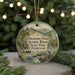 A round ornament with a scenic river landscape and people in a boat, hanging on a string.