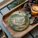 A wooden tray with a decorative ornament featuring a scenic landscape of Hope Island, Washington, surrounded by pine cones and a lit candle.