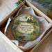 A decorative ornament in a white box, featuring a nature scene with a bird, turtle, and flowers.