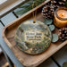 A wooden tray with a decorative ornament featuring a scenic image of Hyner Run State Park in Pennsylvania, accompanied by pine cones and a lit candle.