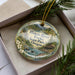 A decorative ornament in a box, featuring a scenic image of the Illinois River and Forks State Park in Oregon.