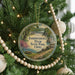 A round ornament on a Christmas tree, featuring a scenic image of Independence Dam State Park, Ohio.